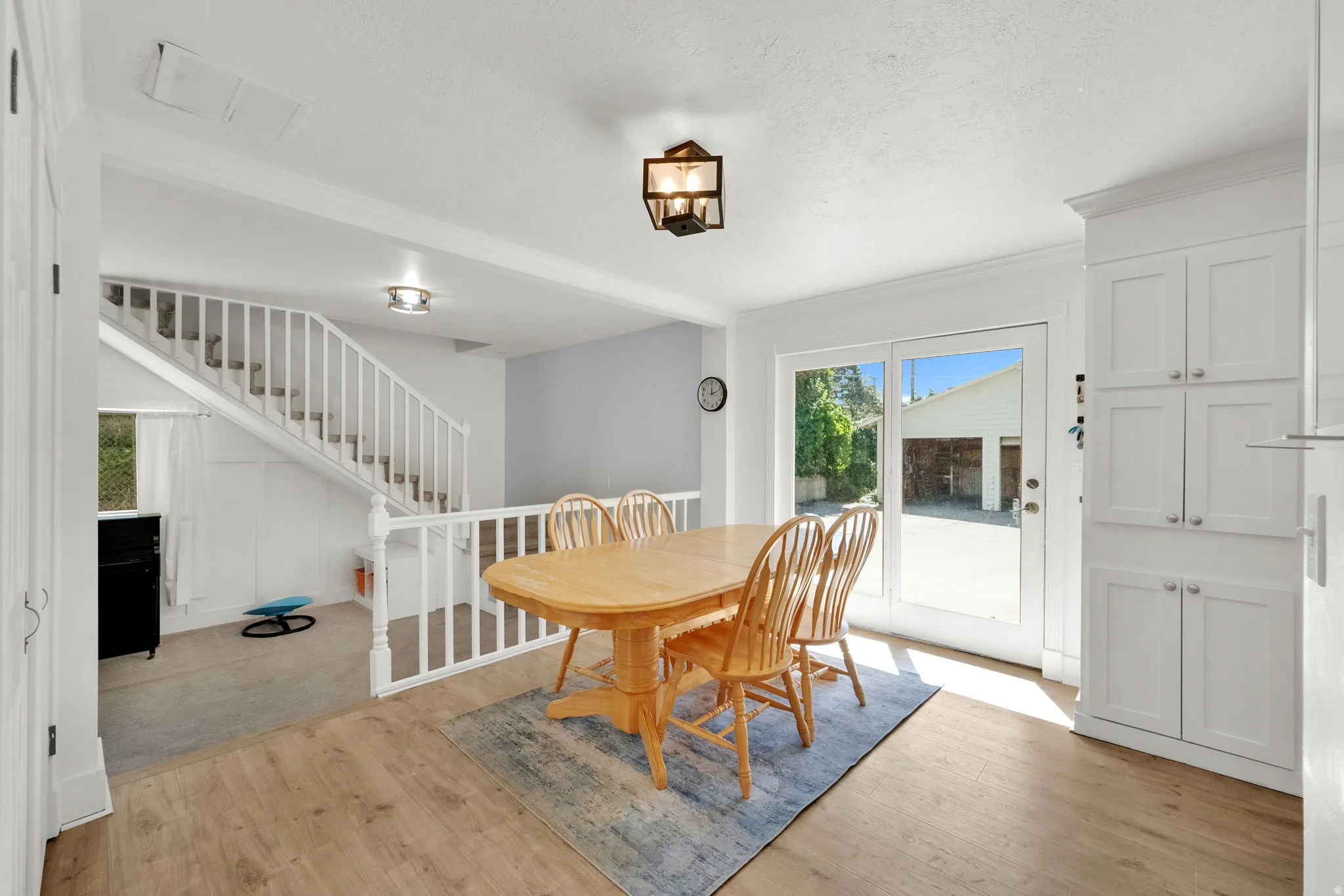 Wood-finish flooring with white trim, built-in cabinetry, and a glass-paneled door