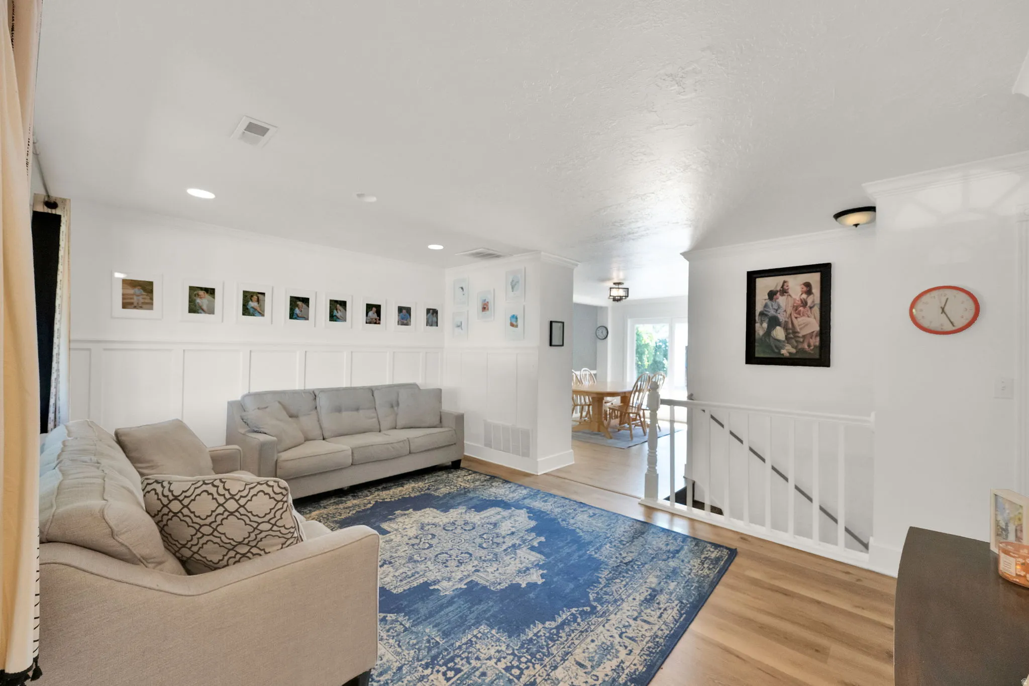 Wood-finish flooring, recessed lighting, wainscoting, and crown molding