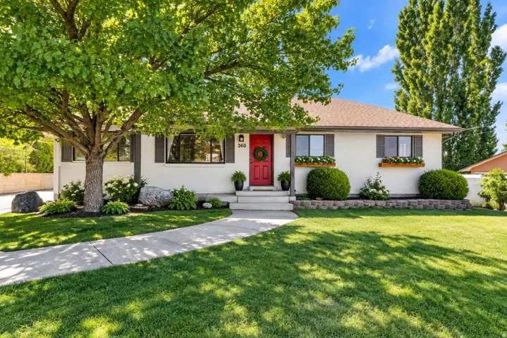 White exterior with a red entry door, gray window shutters, and wood window boxes