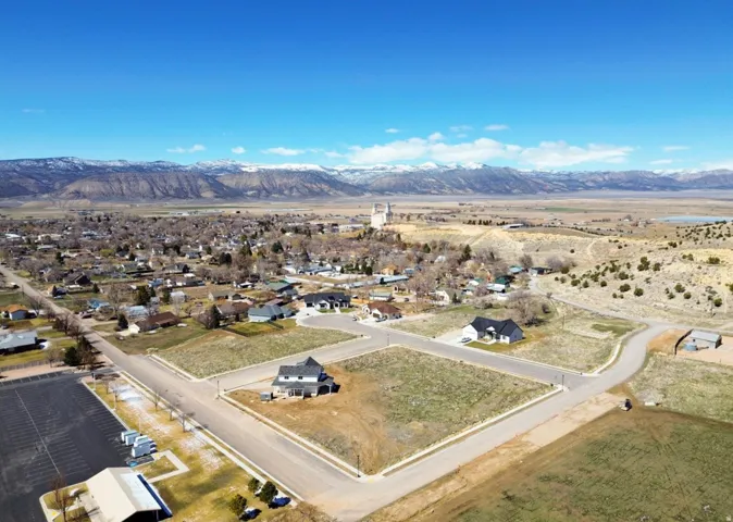 Expansive lot with paved road frontage, surrounded by developing residential properties and distant mountain ranges