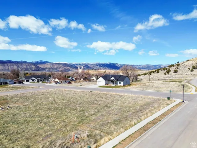 Expansive lot with paved road frontage and sidewalks, set against a backdrop of distant mountains