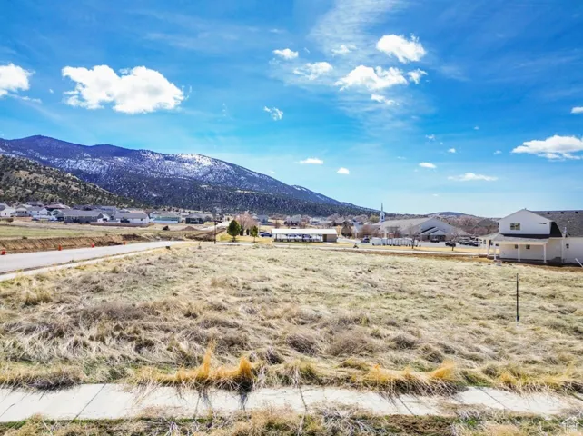 Expansive undeveloped lot featuring a mountain backdrop and a partial sidewalk