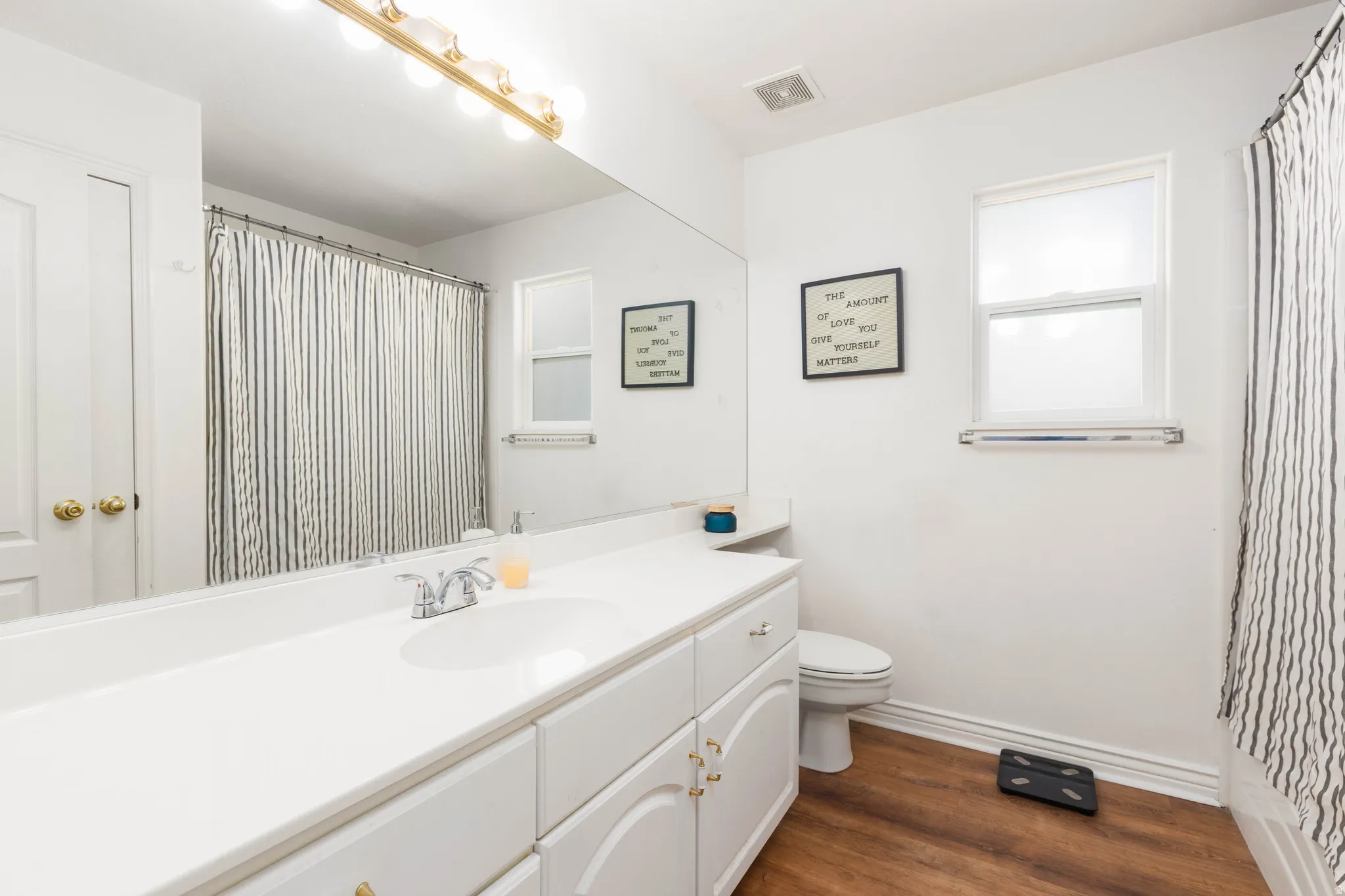 White vanity with integrated sink, chrome faucet, and expansive wall-mounted mirror