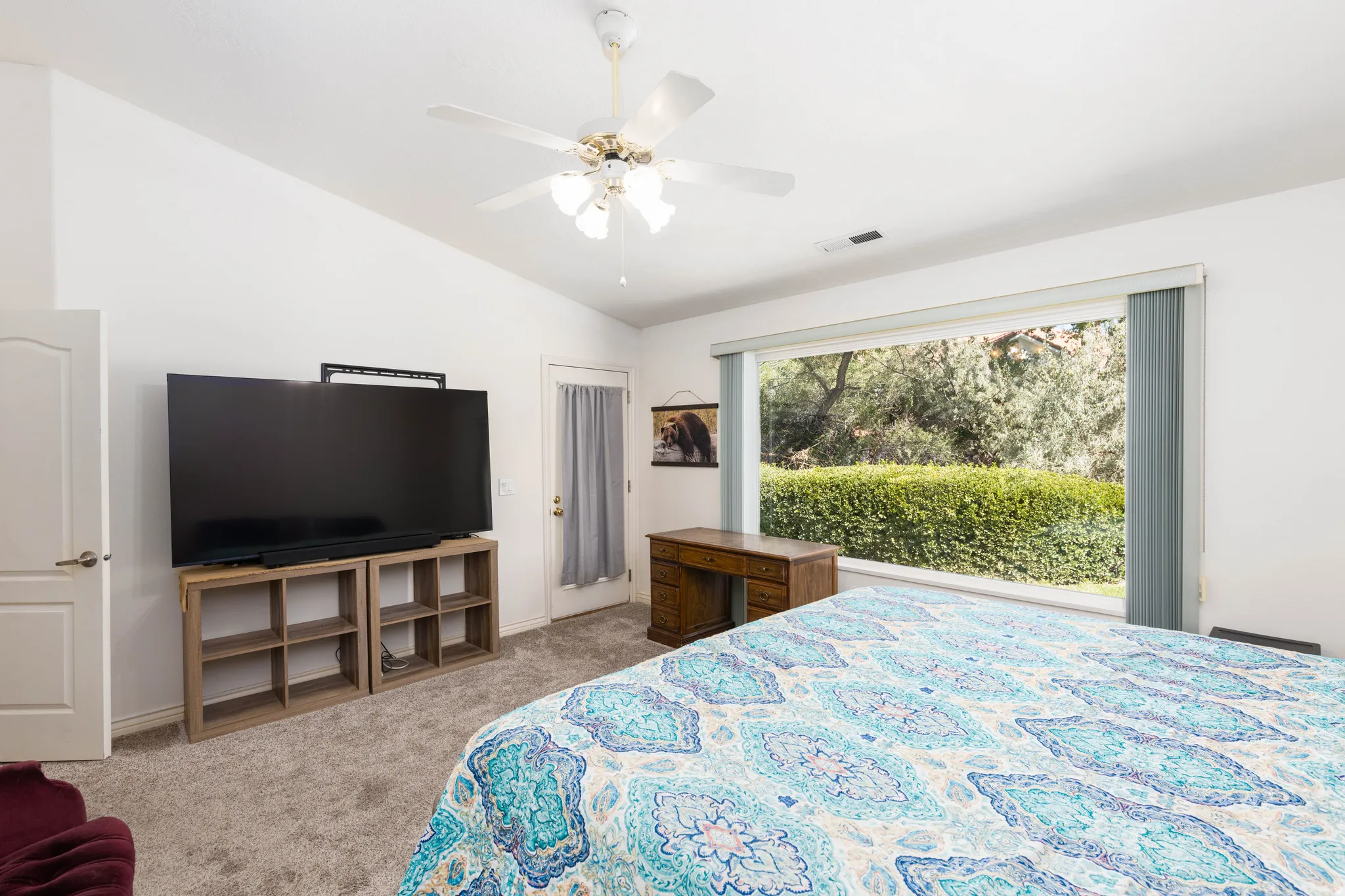 Expansive window with natural light, vaulted ceiling, and carpeted flooring