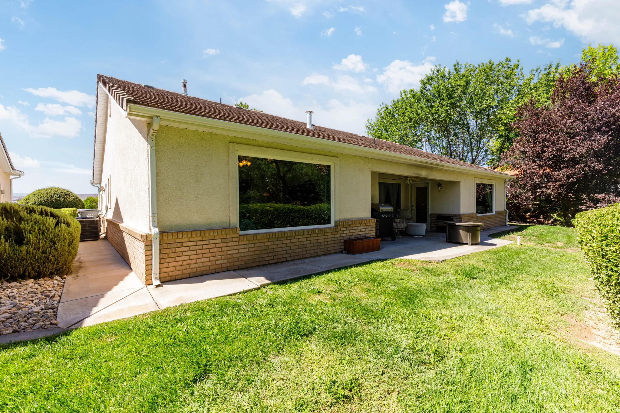 Exterior with stucco siding, a brick foundation, and a covered patio