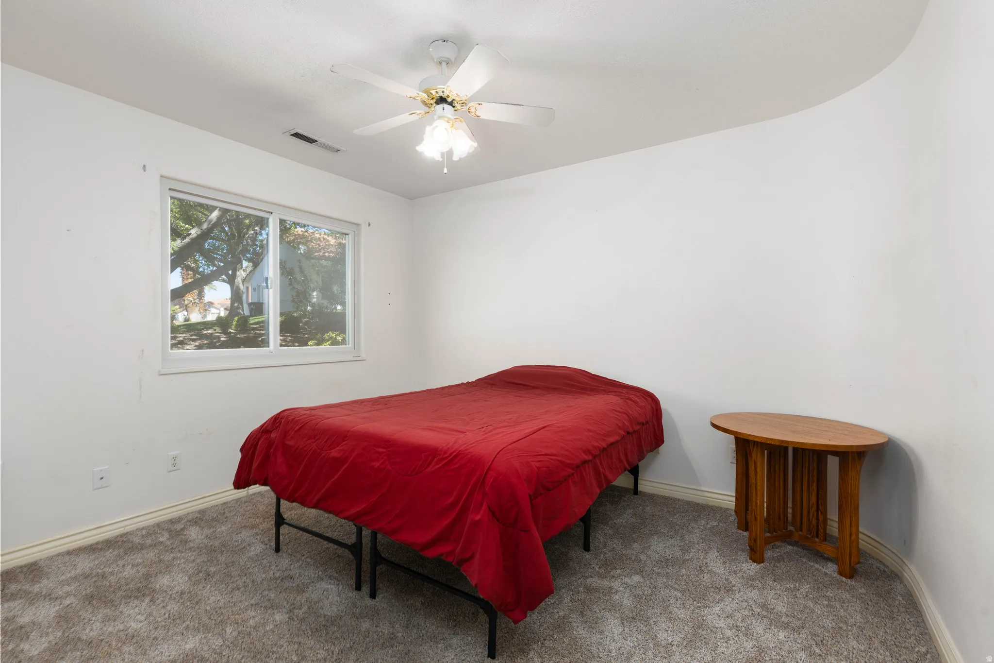 Carpeted room with a ceiling fan, a window, and white walls