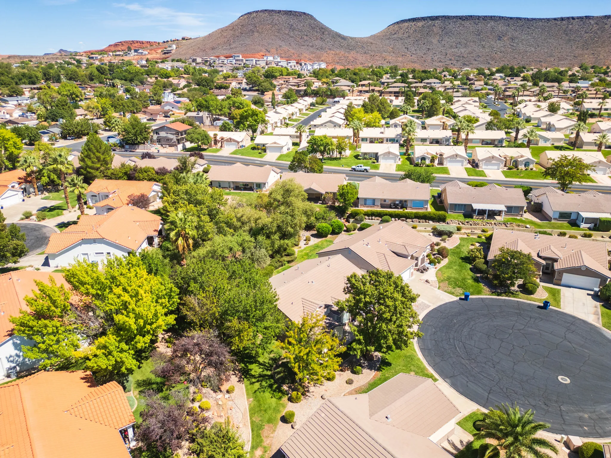 Residential neighborhood featuring mature trees, paved streets, and distant mountain backdrops