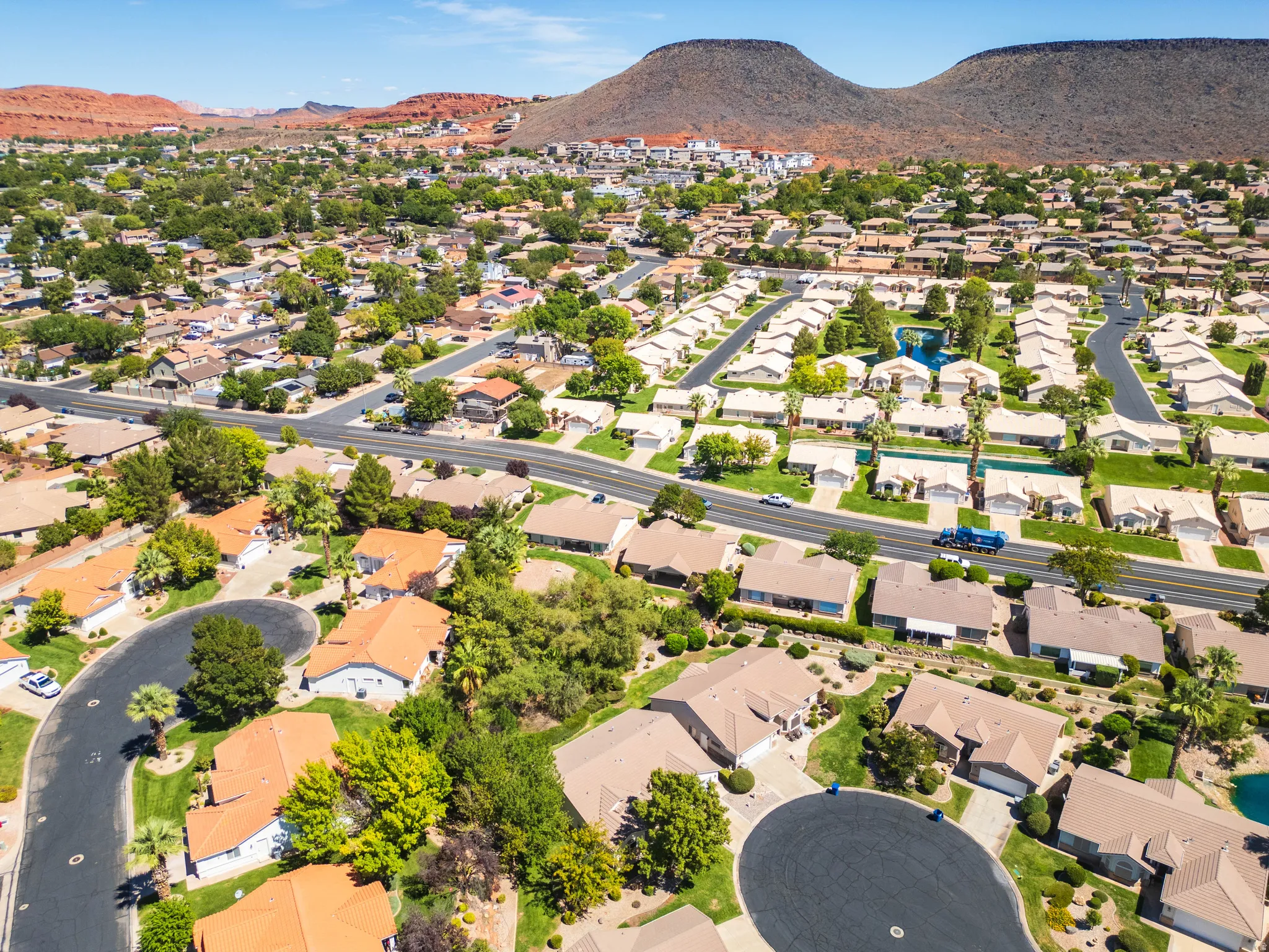 Residential community with established landscaping and paved roadways, set against a mountainous backdrop