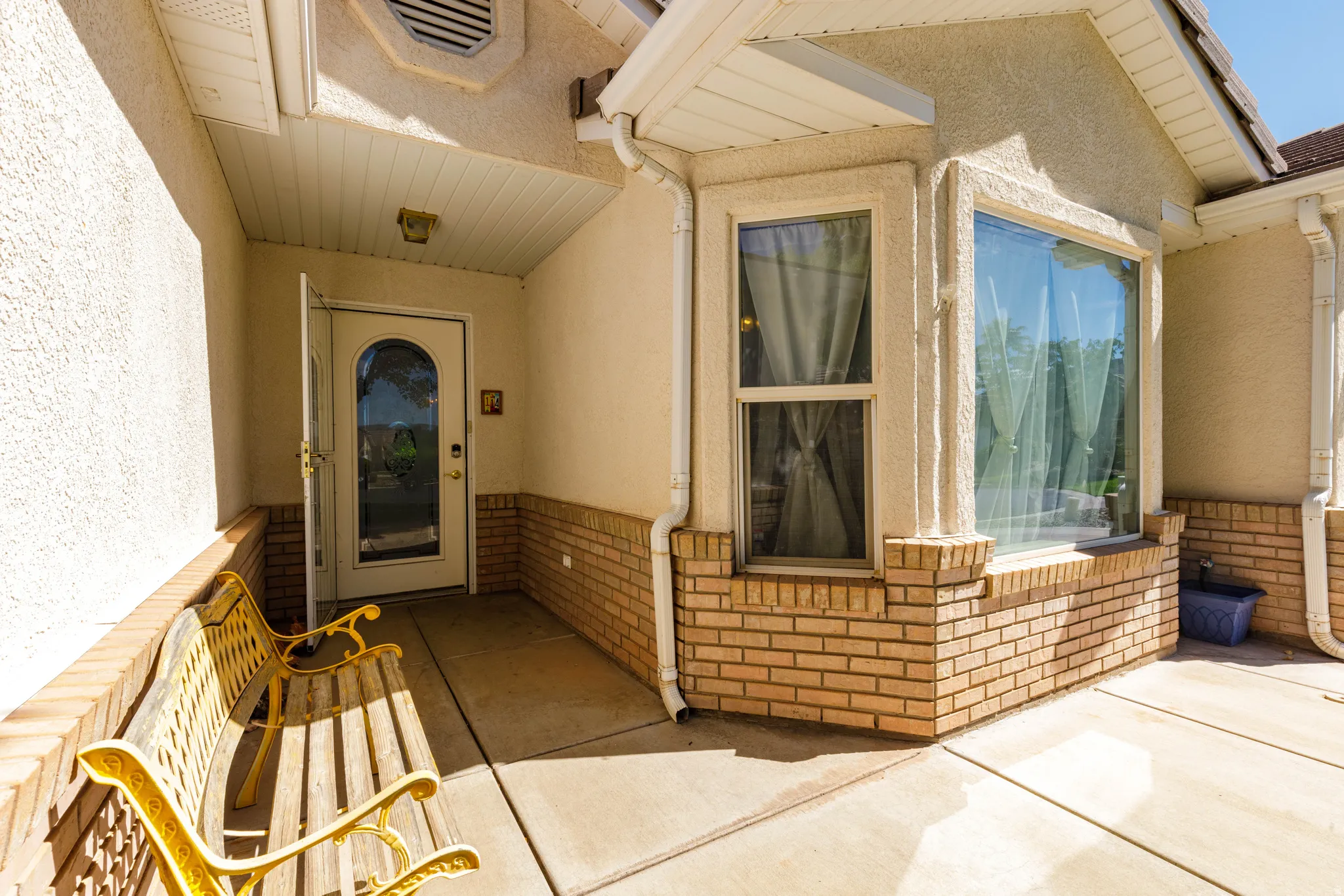 Exterior featuring stucco siding, brick detailing, a covered entryway, and large bay windows