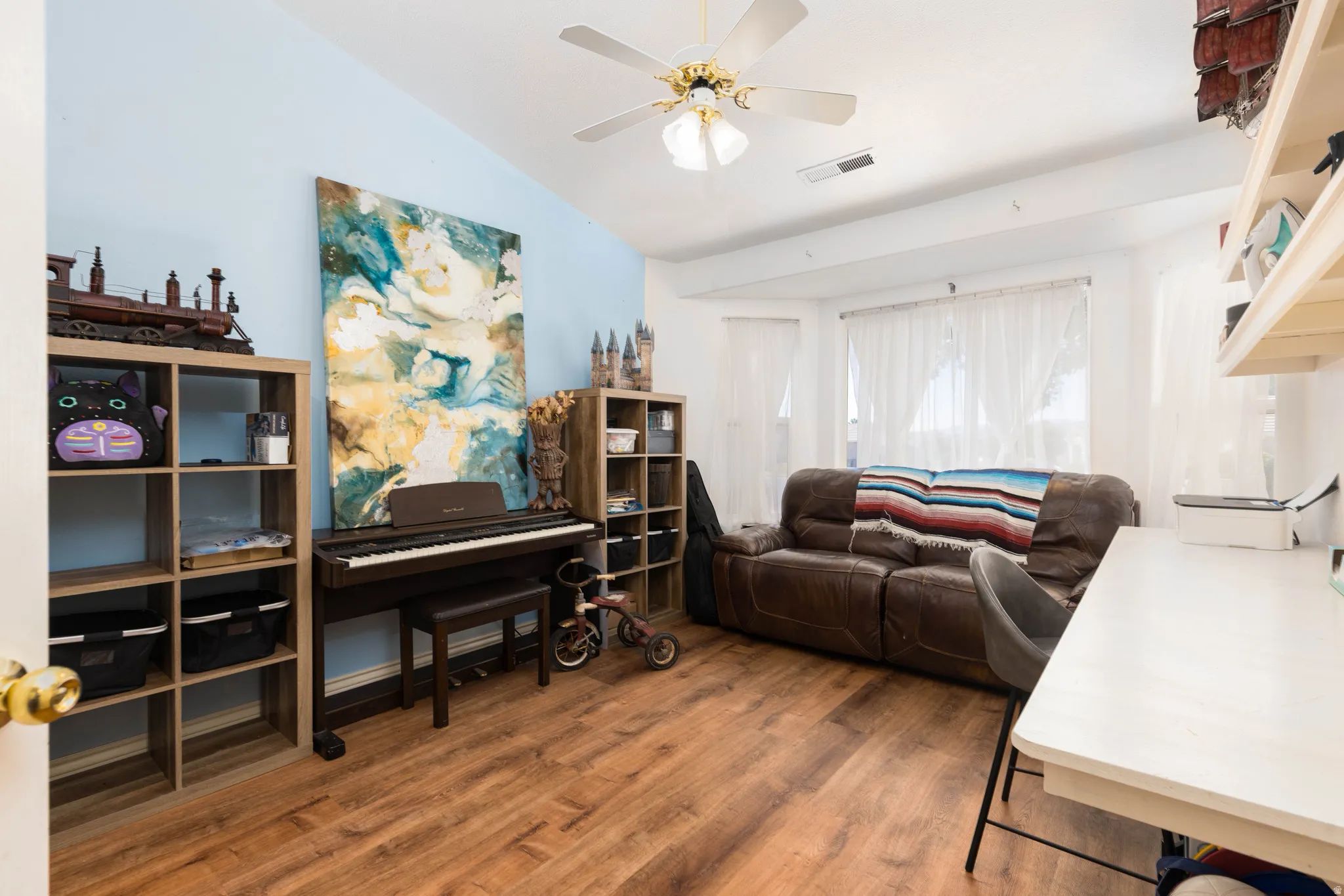 Vaulted ceiling, wood-finish flooring, ceiling fan, built-in shelving, and transom windows