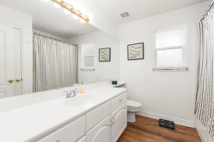 White vanity with integrated sink, chrome faucet, and expansive wall-mounted mirror