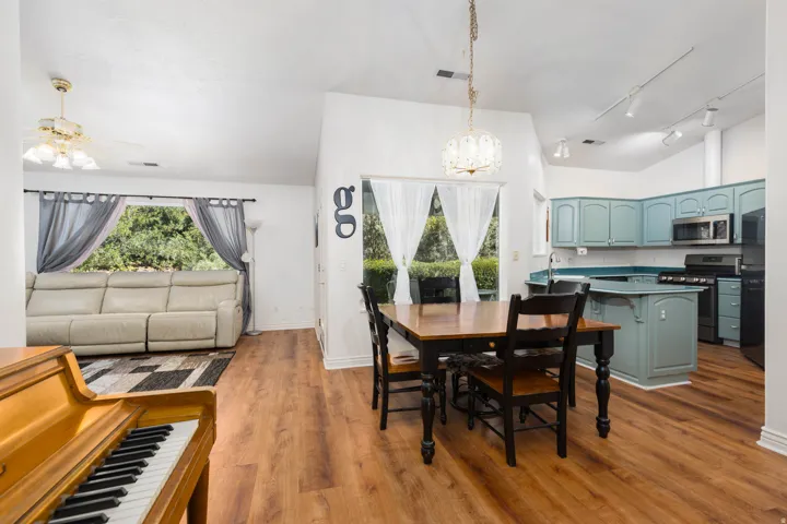 Vaulted ceilings complement the wood-finish flooring throughout this open-concept space, featuring a kitchen with blue cabinetry and an island, plus a dining area with a chandelier