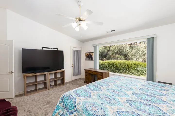 Expansive window with natural light, vaulted ceiling, and carpeted flooring