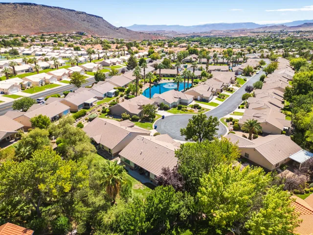 Residential neighborhood with mature trees, a central pond feature, and distant mountainous terrain
