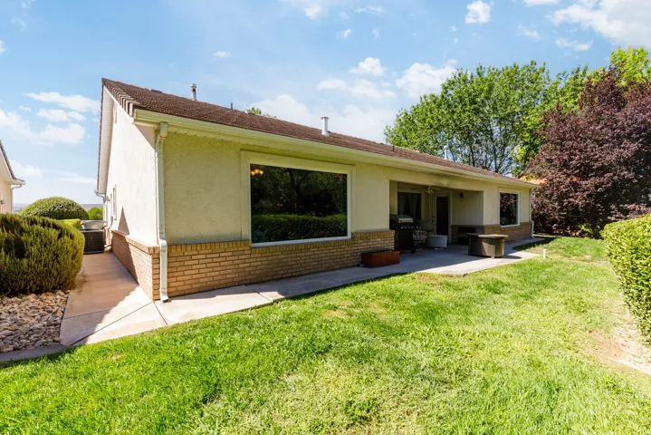 Exterior with stucco siding, a brick foundation, and a covered patio