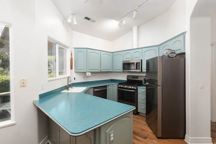 Vaulted ceiling, stainless steel appliances, wood-finish flooring, ample cabinetry, and an integrated sink