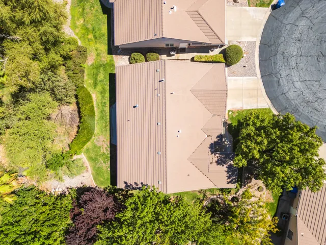 Aerial perspective featuring mature trees, landscaped green spaces, and a residential cul-de-sac