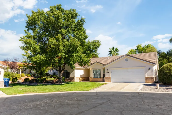 Single-story residence featuring a tile roof, an attached garage, and a concrete driveway