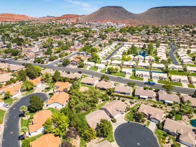 Residential community with established landscaping and paved roadways, set against a mountainous backdrop