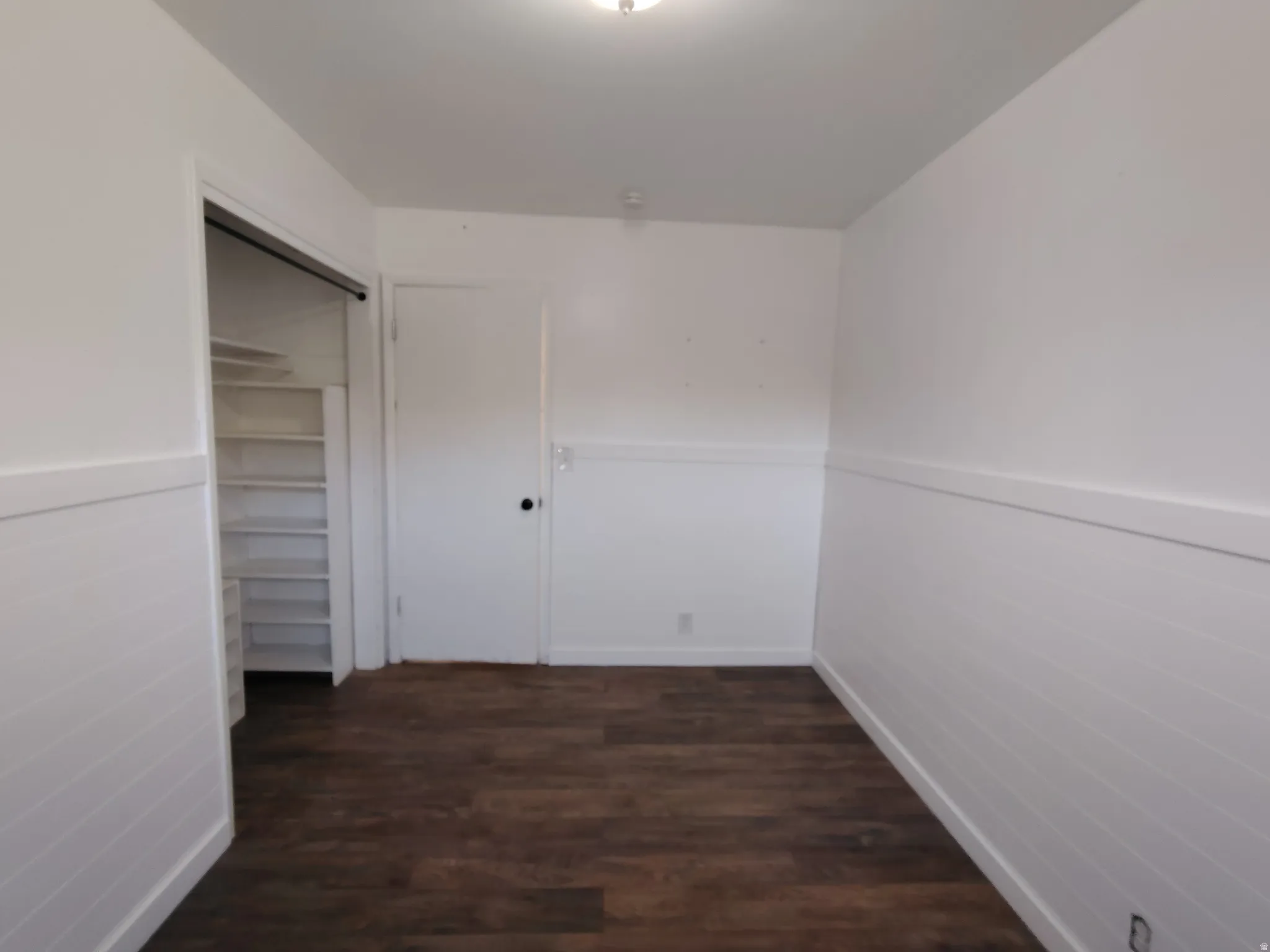 Wood-finish flooring, white wainscoting, and built-in shelving