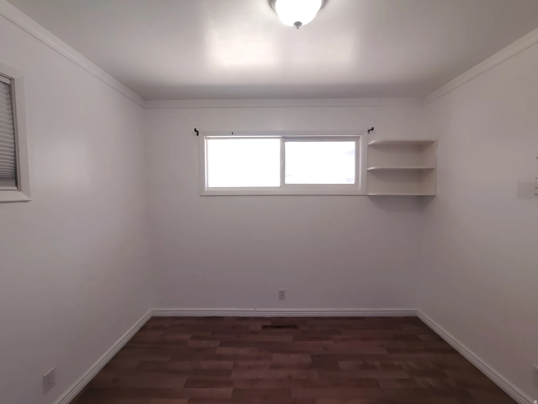 Wood-finish flooring with white trim and crown molding