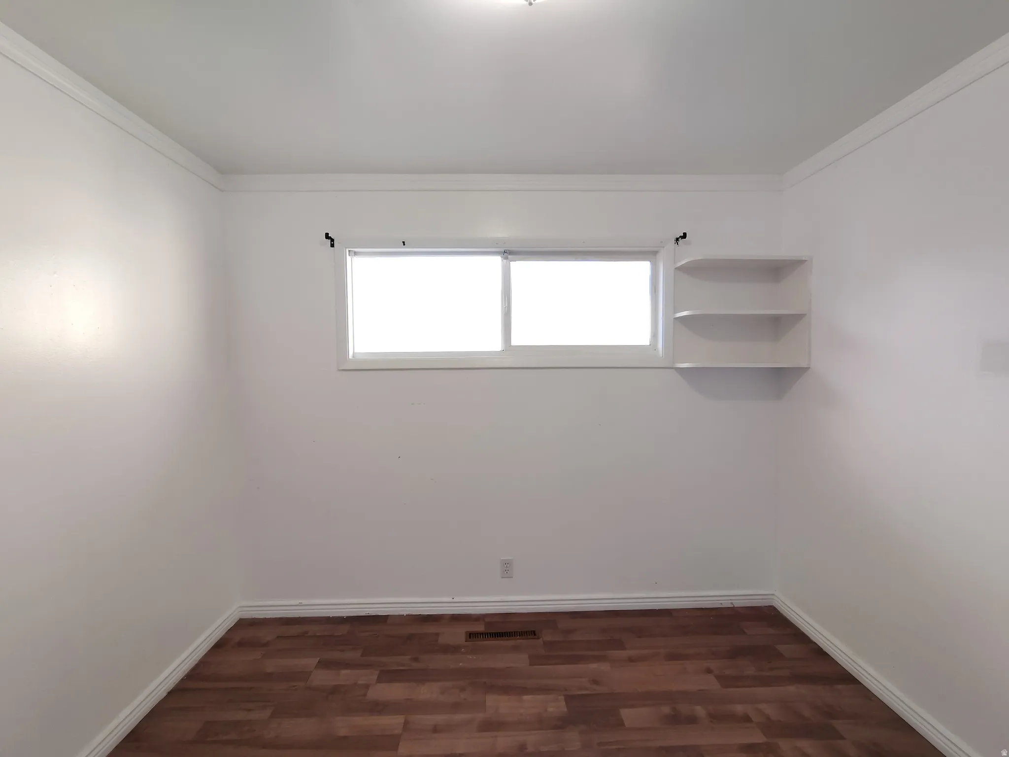 Wood-finish flooring, white walls, crown molding, and built-in shelving