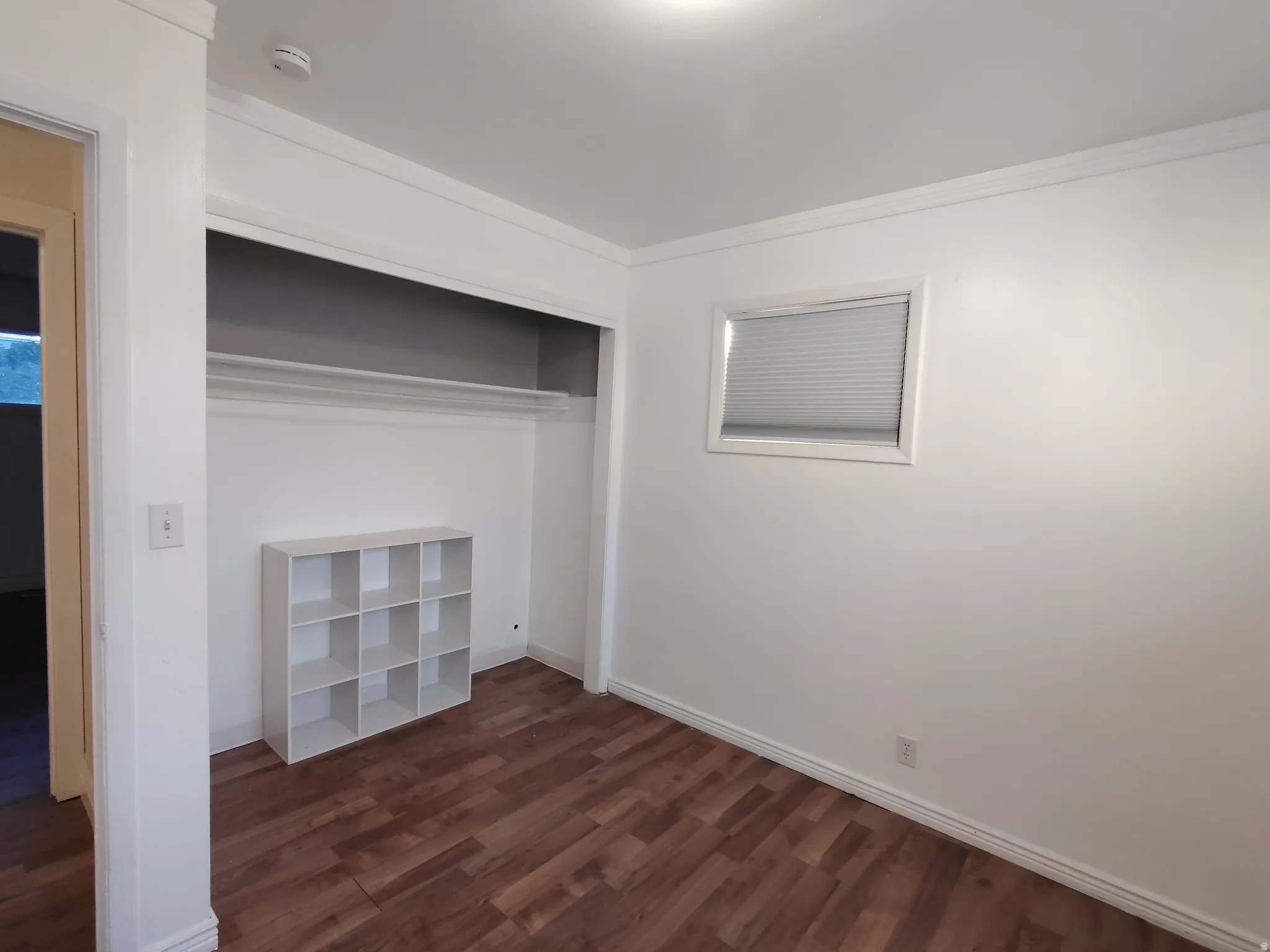 Wood-finish flooring, white walls, and a window with blinds