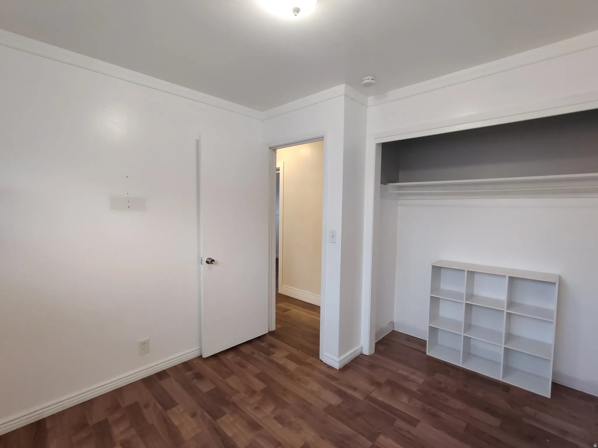 Wood-finish flooring with white trim and crown molding