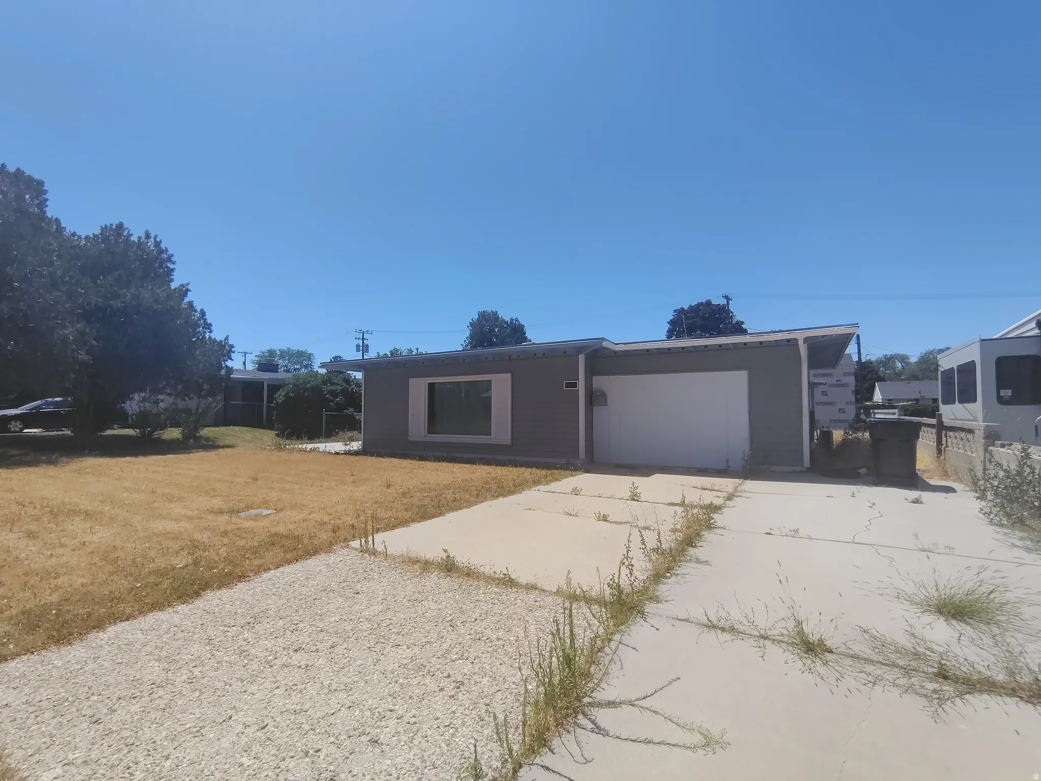Single-story residence featuring a sloped roofline, attached garage with a white door, and a front window with white trim