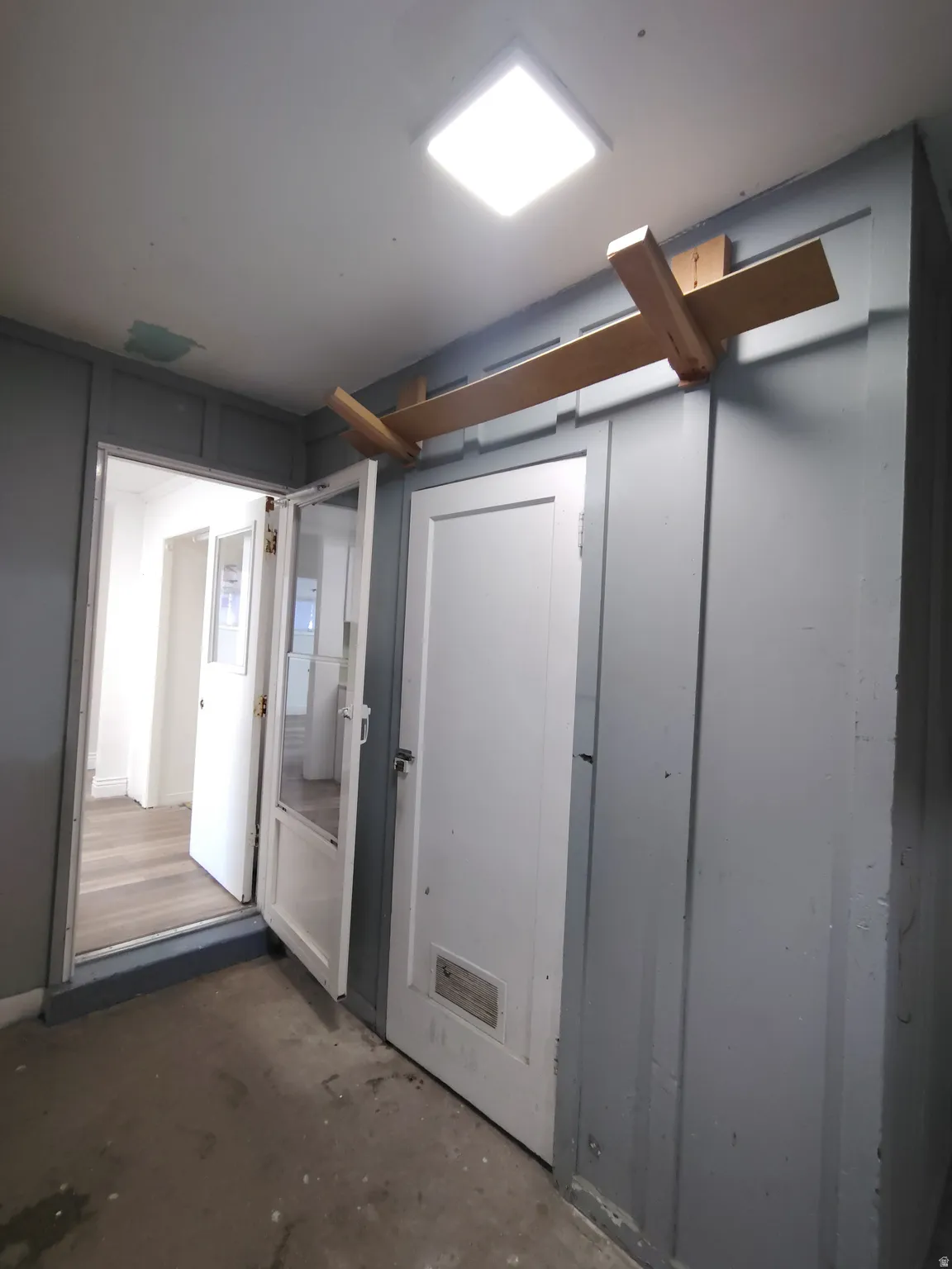 Square ceiling-mounted light fixture, paneled walls, and wood-finish flooring