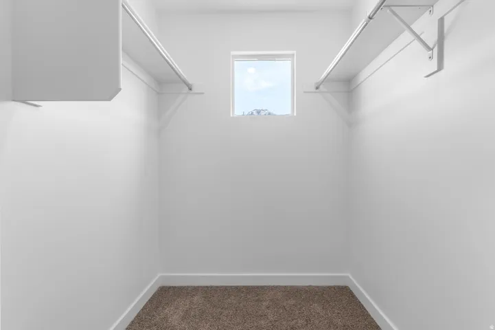 Built-in shelving with hanging rods, overhead storage, and a single window
