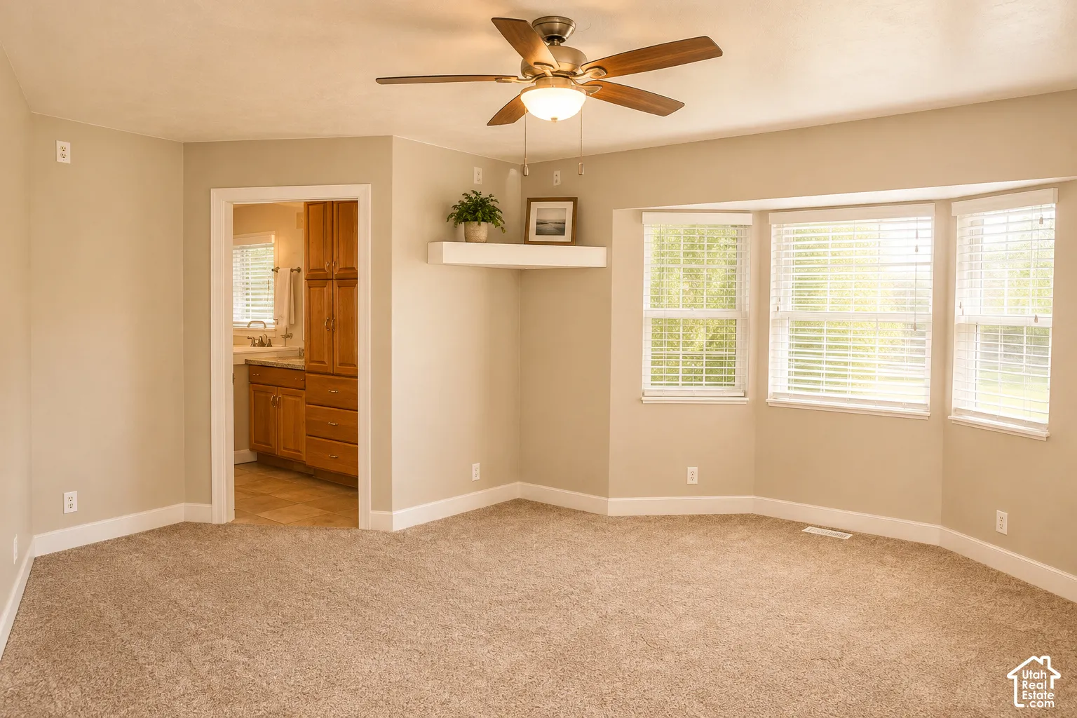 Recessed bay window with multiple panes, ceiling fan light fixture, wall-mounted floating shelf, and neutral carpeting