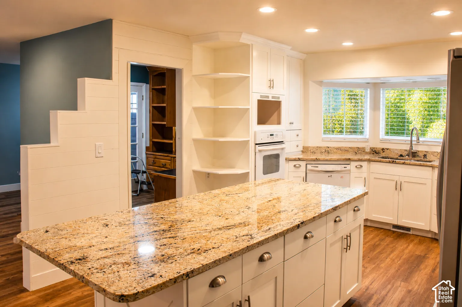 Kitchen featuring an expansive island with a polished stone countertop, built-in white cabinetry, stainless steel appliances, and recessed lighting