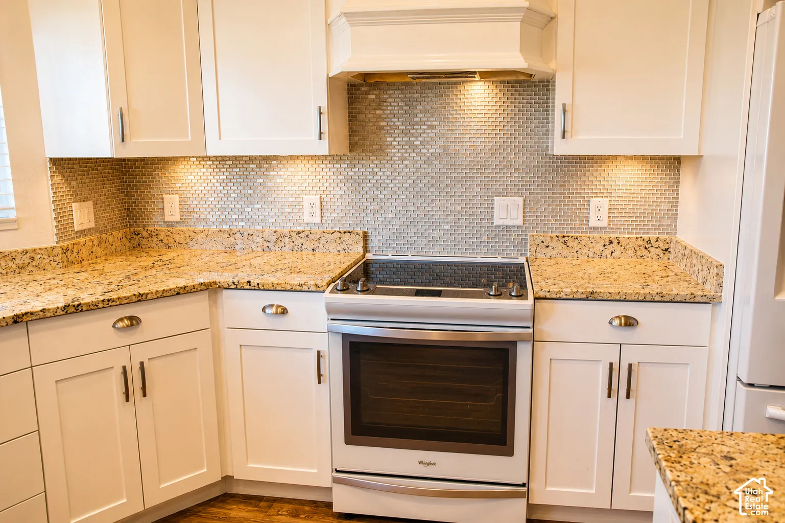 Contemporary kitchen featuring white cabinetry, granite countertops, a tiled backsplash, built-in range, and under-cabinet lighting