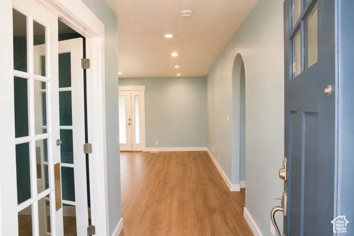 Recessed lighting, wood-finish flooring, arched doorway, French doors, and a paneled front door