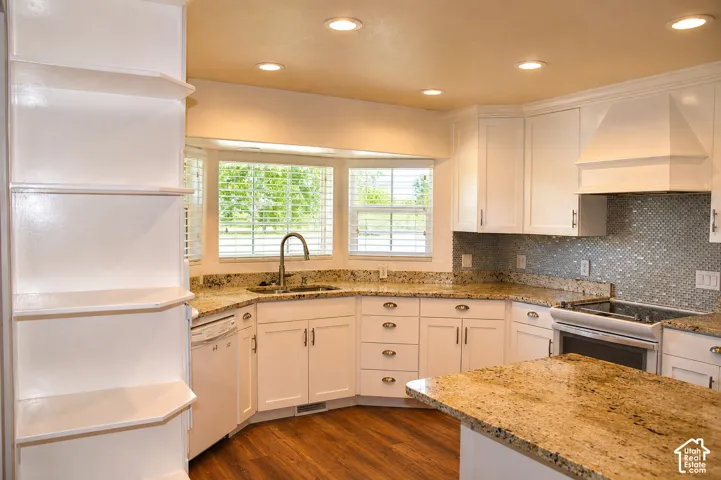 White cabinetry with built-in shelving, granite countertops, and a tiled backsplash