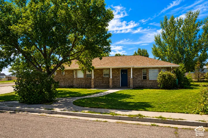 Brick exterior with a covered porch, established trees, and a concrete walkway