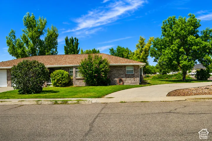 Brick exterior with a brown shingle roof, integrated garage, and a concrete driveway