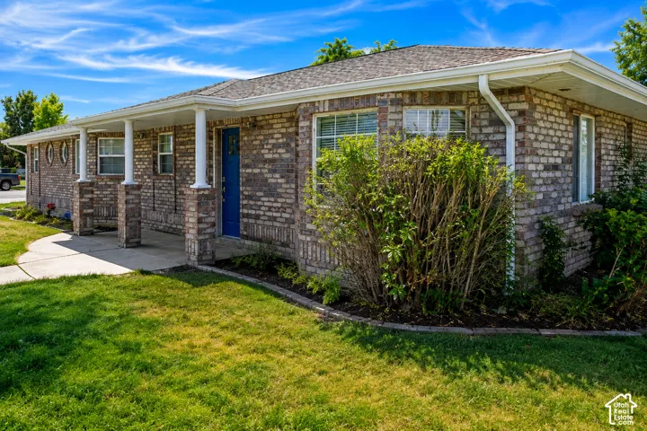 Brick exterior with a covered porch, white columns, blue entry door, and a concrete walkway