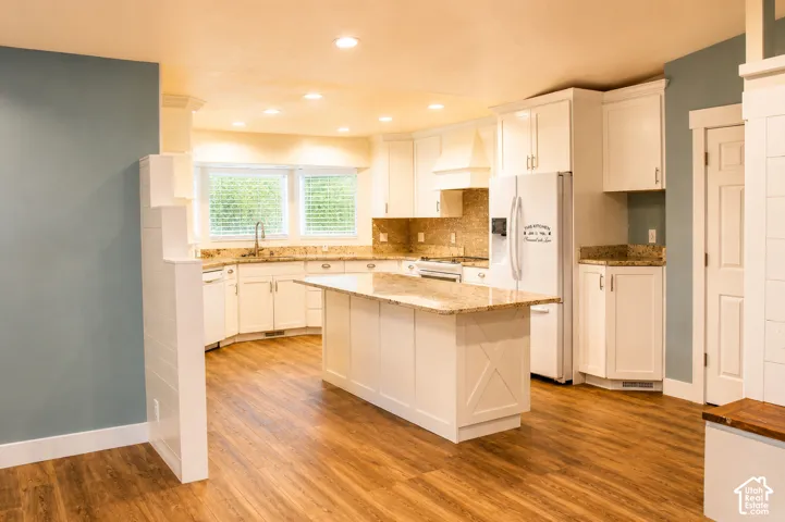 Kitchen featuring white cabinetry, granite countertops, a center island, wood-finish flooring, and recessed lighting