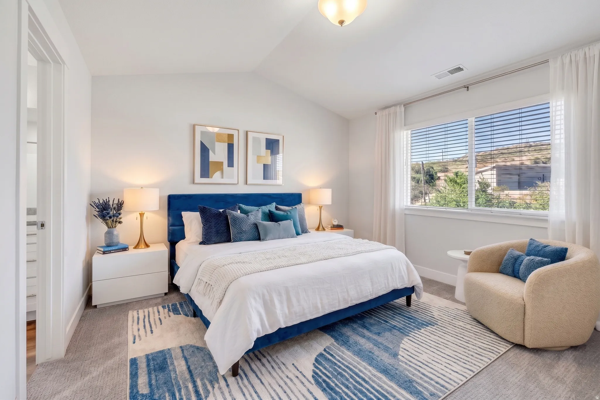 Vaulted ceiling, large window with blinds, soft carpeting, and a white interior door