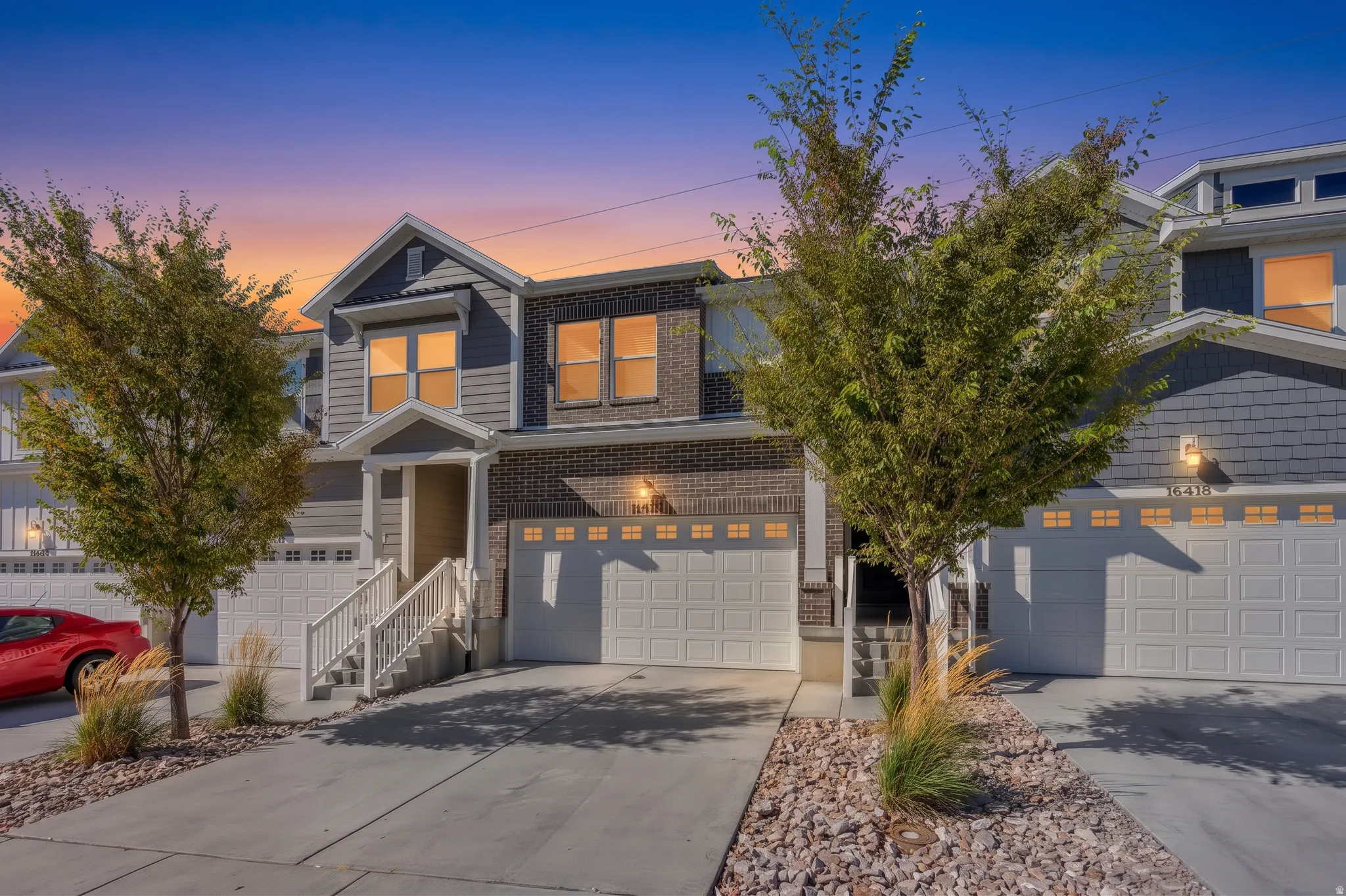 Two-story townhome with a brick and shingle facade, featuring a prominent gable roofline and an attached garage