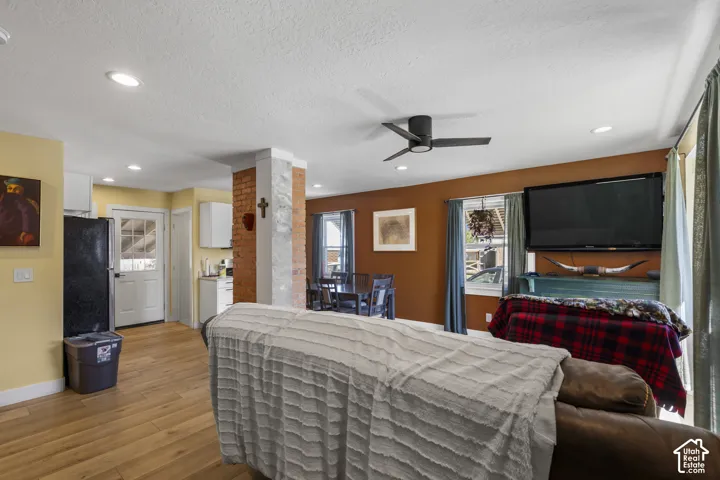 Open-concept living space with wood-finish flooring, recessed lighting, and a contemporary ceiling fan