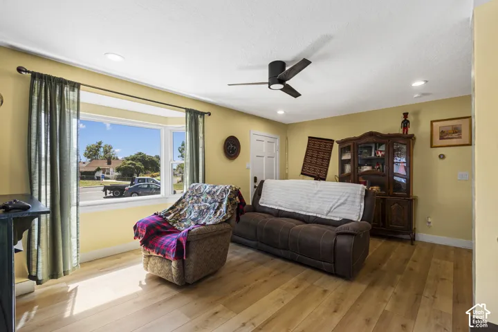 Wood-finish flooring, bay window, recessed lighting, ceiling fan, and white paneled door