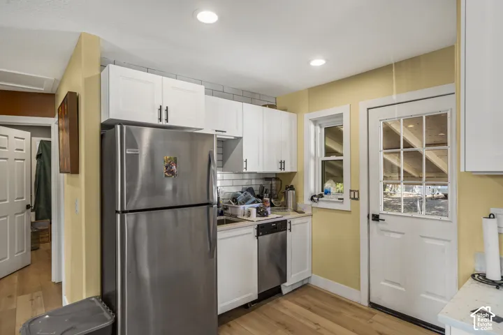 Kitchen featuring white cabinetry, stainless steel appliances, wood-finish flooring, and a glass-paneled exterior door