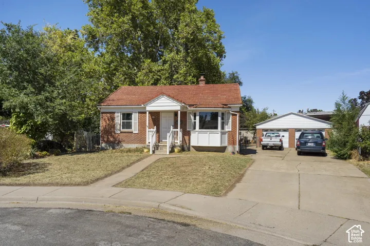 Brick residence featuring a covered front porch, a bay window, a tile roof, and an attached two-car garage
