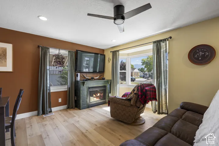 Living area featuring wood-finish flooring, a ceiling fan, recessed lighting, and a bay window