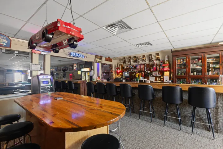 Bar area with a wood-finish bar top, built-in cabinetry, and carpeted flooring