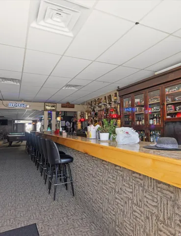 Long bar with integrated seating, drop ceiling, and patterned carpet