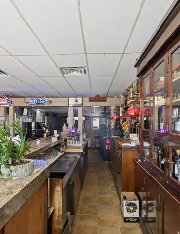Bar area featuring a stone-finish countertop, wood-finish cabinetry, tile flooring, and a drop ceiling